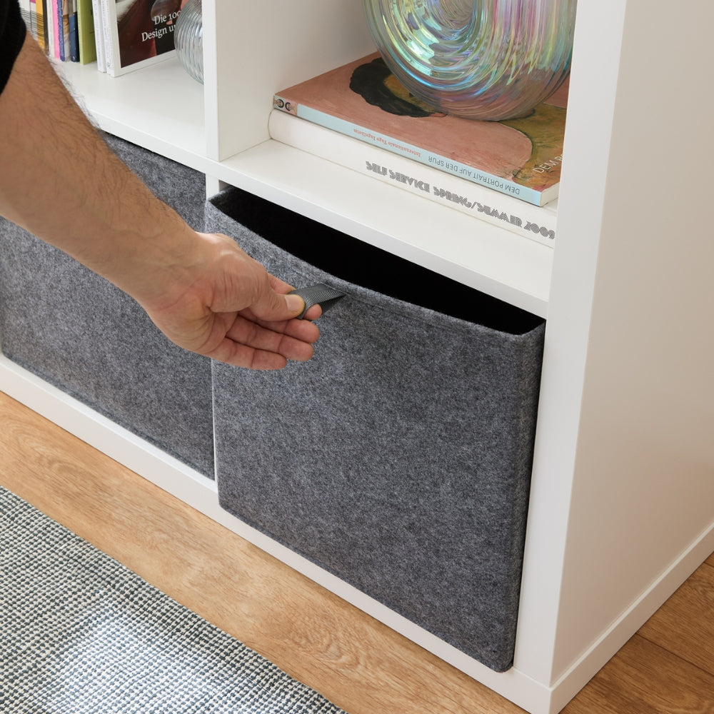 Eine Hand zieht eine Filzbox an der Grifflasche aus dem Kallax Regal.