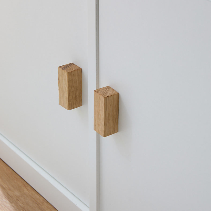 Nahaufnahme von 2 Holzgriffen aus Eiche, die an einer weißen Kallax Tür befestigt sind.