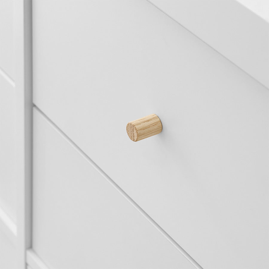 Detailaufnahme von einem rundem Möbelgriff aus Eiche, der an einer weißen Schubladen befestigt wurde.