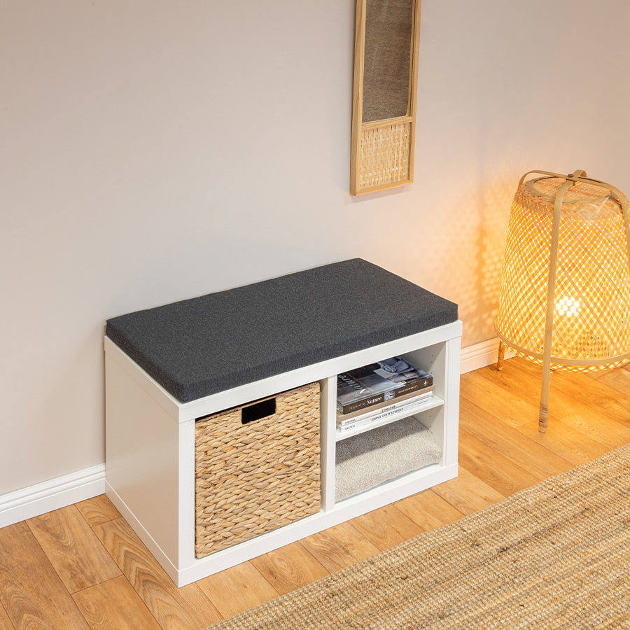 Sitzpolster in Anthrazit auf weißem 2er Kallax Regal, genutzt als Sitzbank. Diese ist einem Korb und Büchern gefüllt.