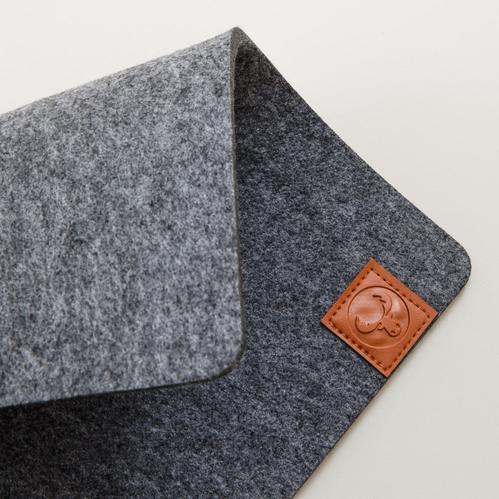 Details einer grau melierten Kallax Bankauflage aus Filz mit einem New Swedish Design Logo aus braunem Leder.