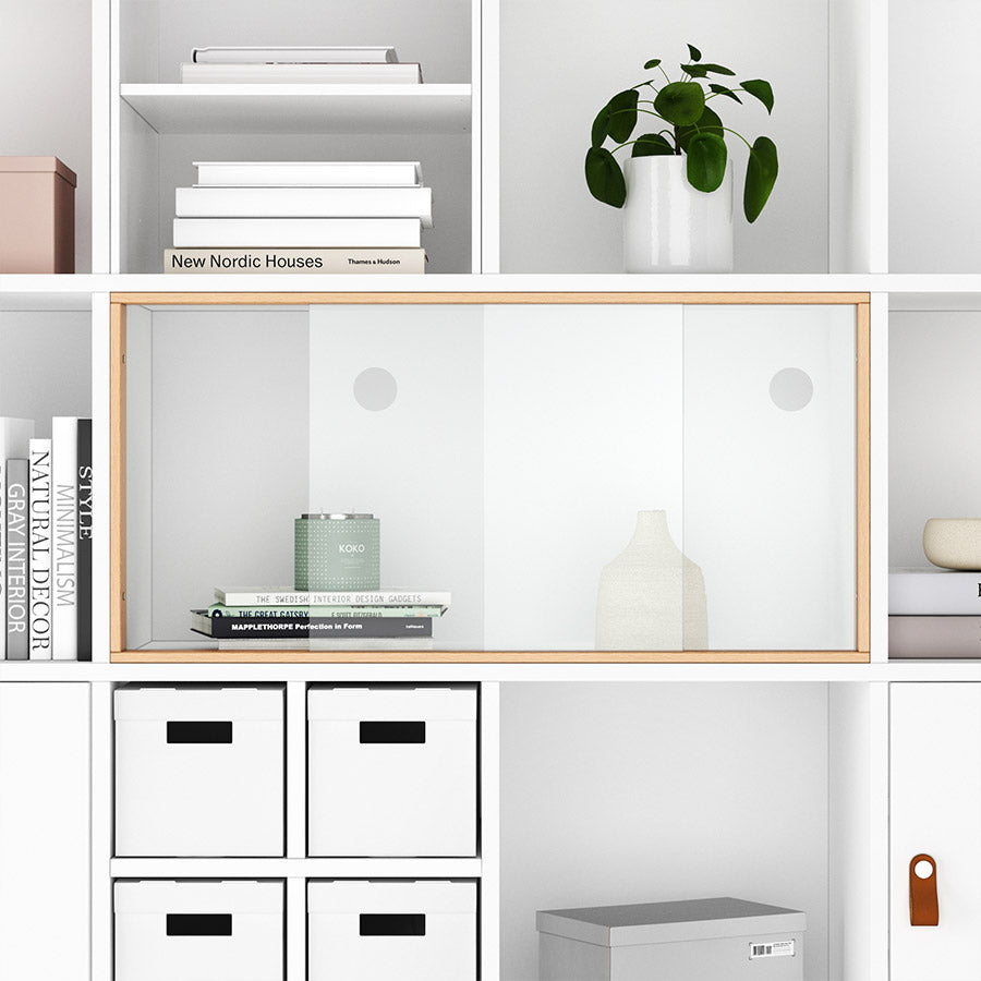 Frontansicht eines Kallas Regals mit einer geschlossenen Schiebetür aus Glas und einem Holzrahmen.