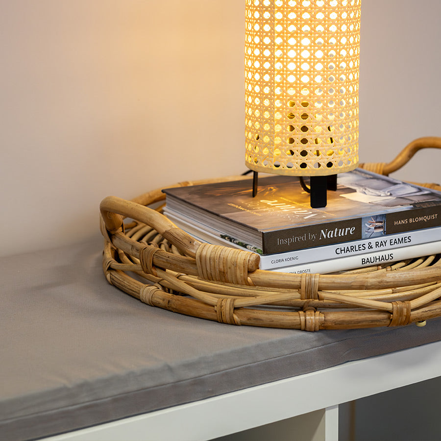 Nahaufnahme des Sitzpolsters in Hellgrau und schönen Dekoobjekten (natürliche Lampe auf geflochtenem Serviertablett)