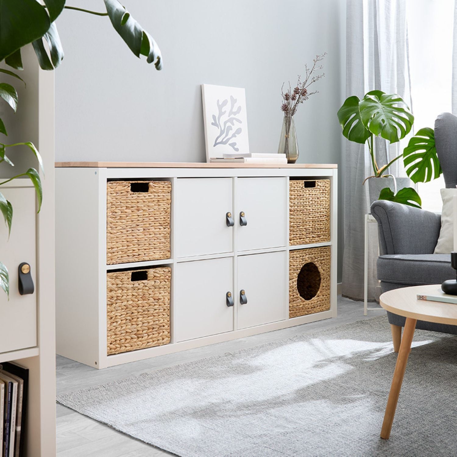 Weißes Kallax Regal von IKEA mit Türen, Ledergriffen und Aufbewahrungskörben.