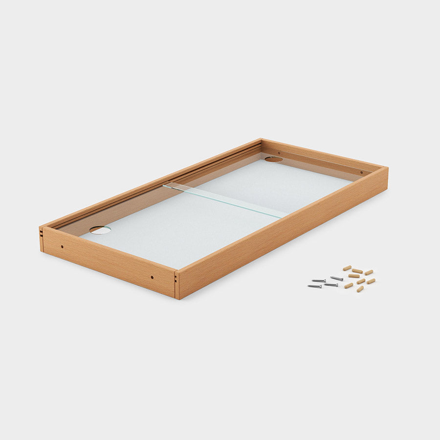 Einzelne Schiebetür mit einem Holzrahmen und Glasscheiben. Daneben liegt das Montagematerial.